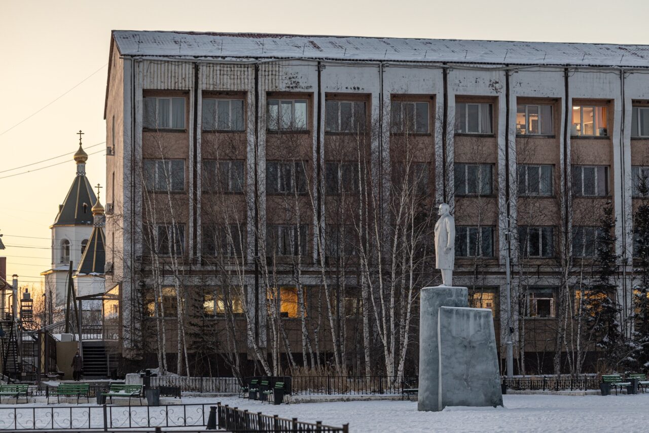Памятник Ленину стоит между большим зданием районной администрацией и маленьким зданием мэрии